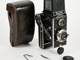 un vieil appareil photo avec un étui en cuir à côté