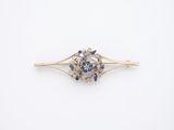 un gros plan sur une broche en forme de fleur, sertie de diamants et de saphirs