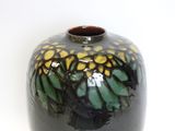 a black vase with yellow and green designs on it