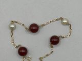 un gros plan sur un bracelet à chaîne en or orné de perles rouges