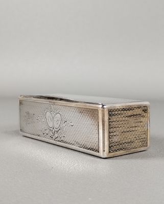 un étui à cigarettes en argent posé sur une surface blanche