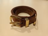 une ceinture marron avec une boucle dorée posée sur une table