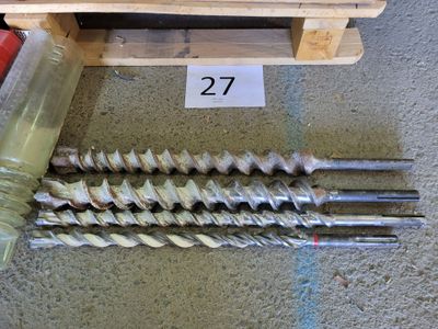 a pile of drill bits sitting on the floor next to a wooden crate
