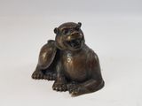 bronze figurine of a monkey sitting on a white surface