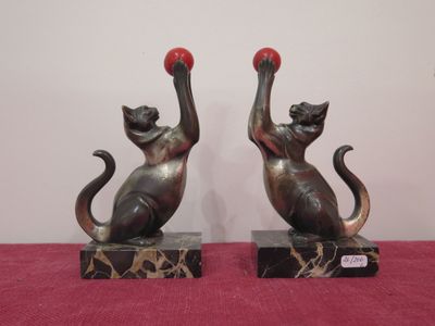 two statues of cats with red balls on them