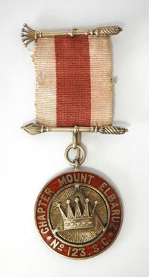 a close up of a medal on a white surface with a red ribbon