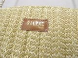 beige straw bag with a leather label on it sitting on a table