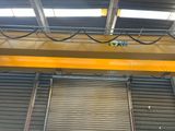 an overhead crane in a warehouse with the door open