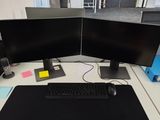 a desk with two monitors and a keyboard on it