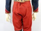 the back view of a man in red pants and a blue jacket