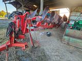 a red tractor parked in a barn with other farm equipment