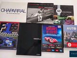several books on a white table with a red car in front of them