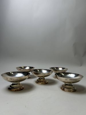 four silver plated bowls on pedestals on a white surface