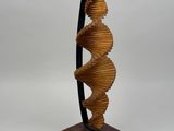une photo représentant une sculpture en forme de spirale posée sur un socle en bois