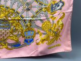 a pink and gold scarf with a picture of a coat of arms on it