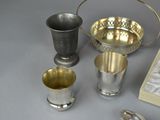 silver cups and spoons on a table next to a book