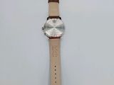 a close up of a watch on a white surface with a tag
