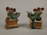 pair of ceramic figurines of a man and a woman sitting on a box