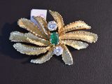 a gold brooch with a green stone in it