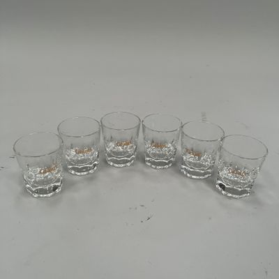 six verres de whisky posés sur une table blanche, sur fond blanc