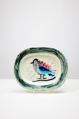 une petite assiette sur laquelle est représenté un oiseau, posée sur une table