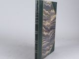 an old book with a green cover sitting on a white surface