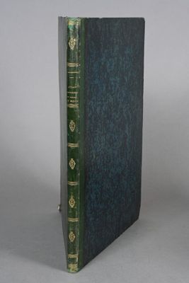 an old book sitting on top of a table next to a white wall