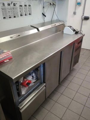 plan de travail en acier inoxydable dans une cuisine professionnelle équipée d'un réfrigérateur