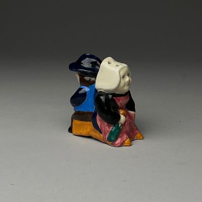 une figurine représentant un homme et une femme assis sur un banc