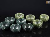 six bols en marbre vert posés sur une table noire