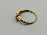 a close up of a gold ring with a red stone on it