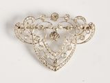 a close up of a heart shaped brooch with pearls on it