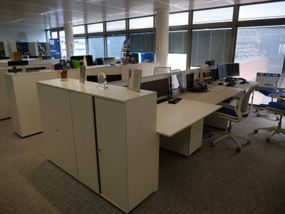 Il y a de nombreux bureaux et chaises dans ce bureau, d'où l'on a une vue sur la ville.