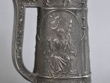an old silver beer mug with a bird on top of it