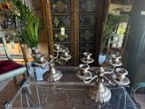 a glass table with a bunch of silver vases on it