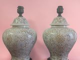 une paire de vases verts posés sur des socles en bois, sur fond rose