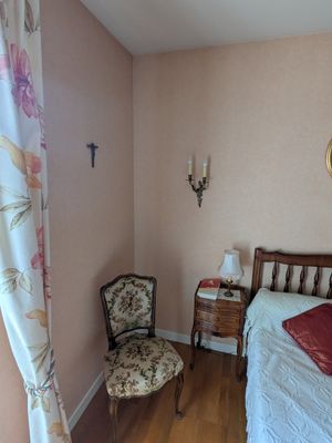 une chambre avec un lit, une chaise et un miroir accroché au mur