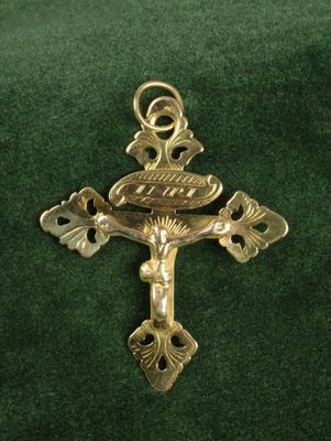 gold cross with a bird on it on a green cloth