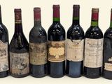 six bottles of wine are lined up in a row on a white surface