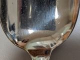 a close up of a spoon with a reflection of a person in the mirror