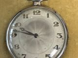 une montre de poche en argent accrochée au mur