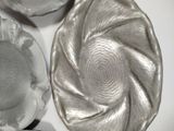 three silver dishes on a white table