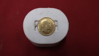 une pièce d'or posée sur une boîte blanche