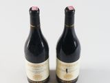 two bottles of wine sitting next to each other on a white surface