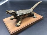 figurine en bronze représentant un lézard, posée sur un socle en bois