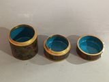 three blue and gold cups sitting on top of a white table