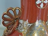 a red vase with gold and white designs on it