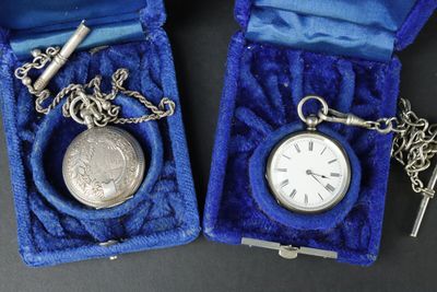 deux montres de poche en argent et une clé dans un étui bleu
