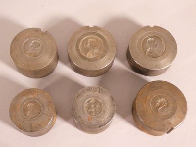 six vieux boutons métalliques posés sur une surface blanche