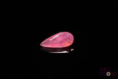 une opale de feu rose de forme ovale posée sur un fond noir